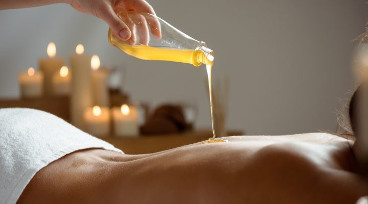 Honey pouring on girl's naked back in spa salon. Copy space.